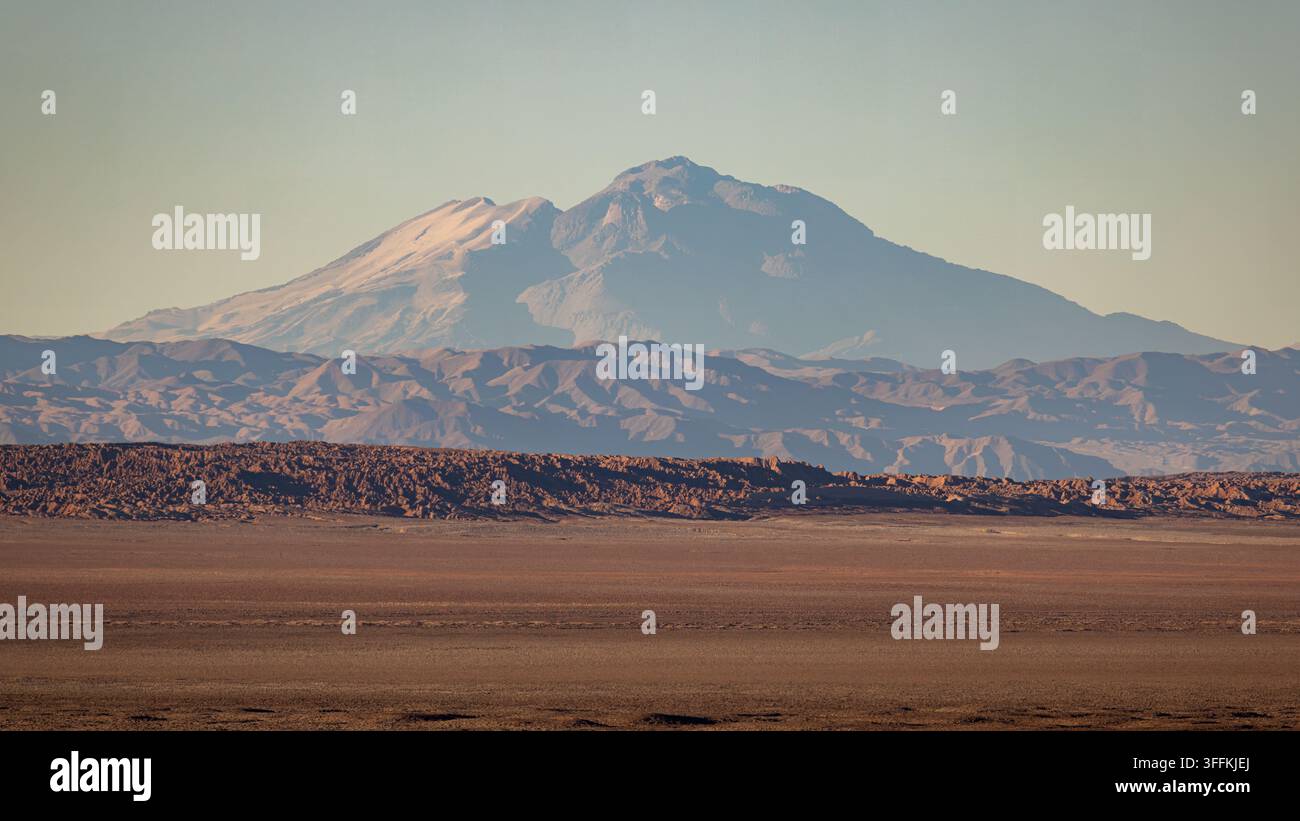 View of the vast arid landscape of the Atacama desert with rugged mountain ranges under a clear sky in Chile. Stock Photo
