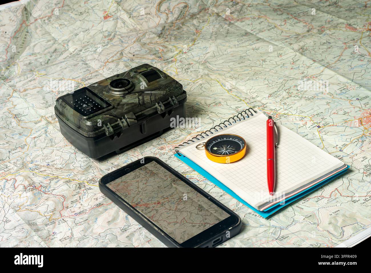 Outdoor navigation planning with trail camera, map, and smartphone Stock Photo