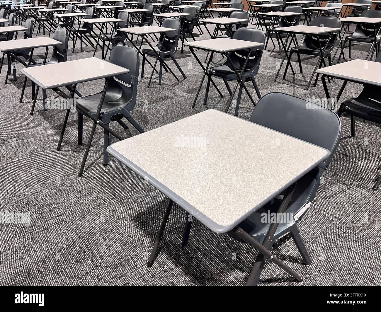 Empty chairs and tables in grey classroom. Stock Photo
