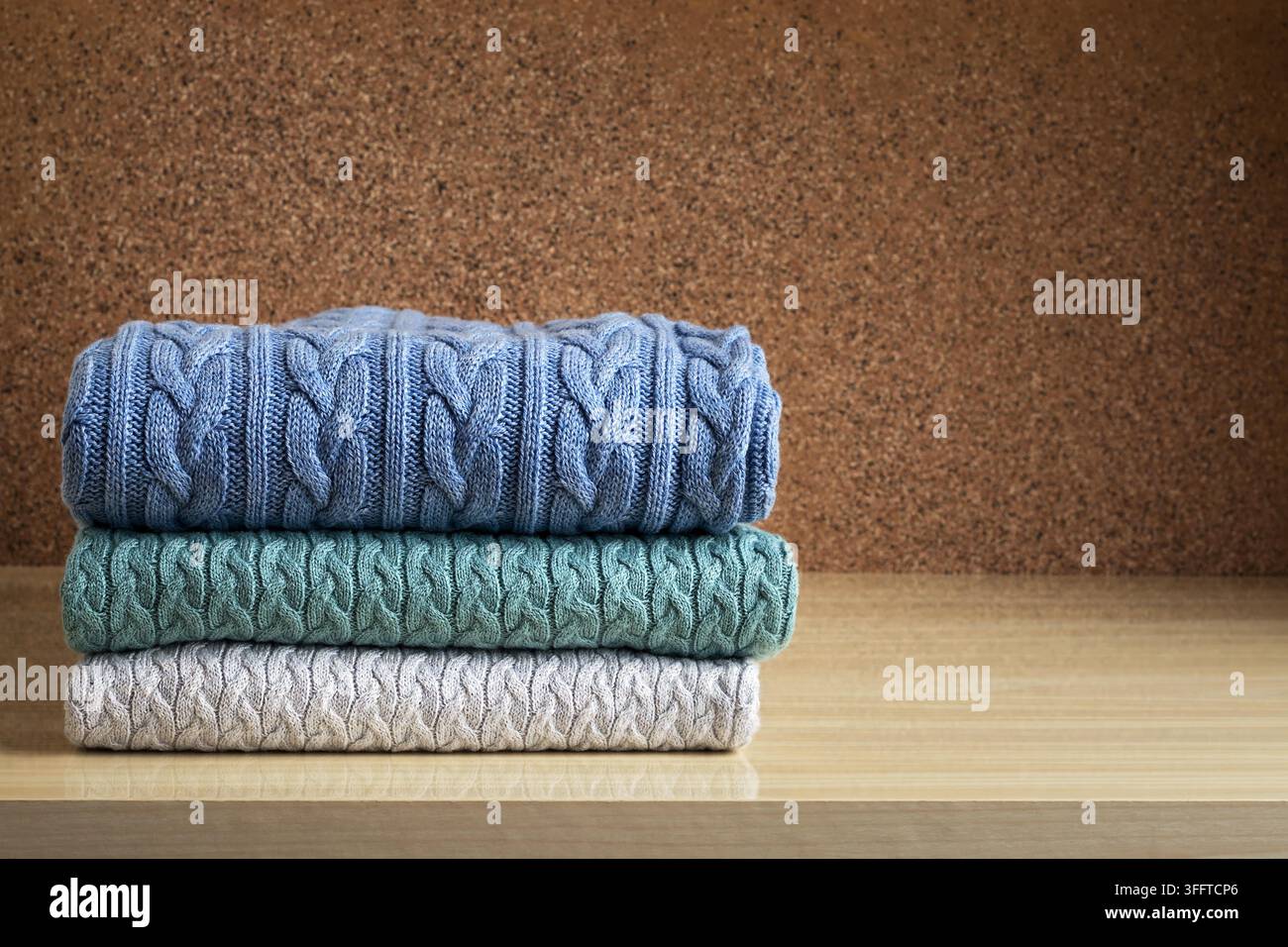 A stack of clothes, colored knitted woolen sweaters on the table Stock Photo