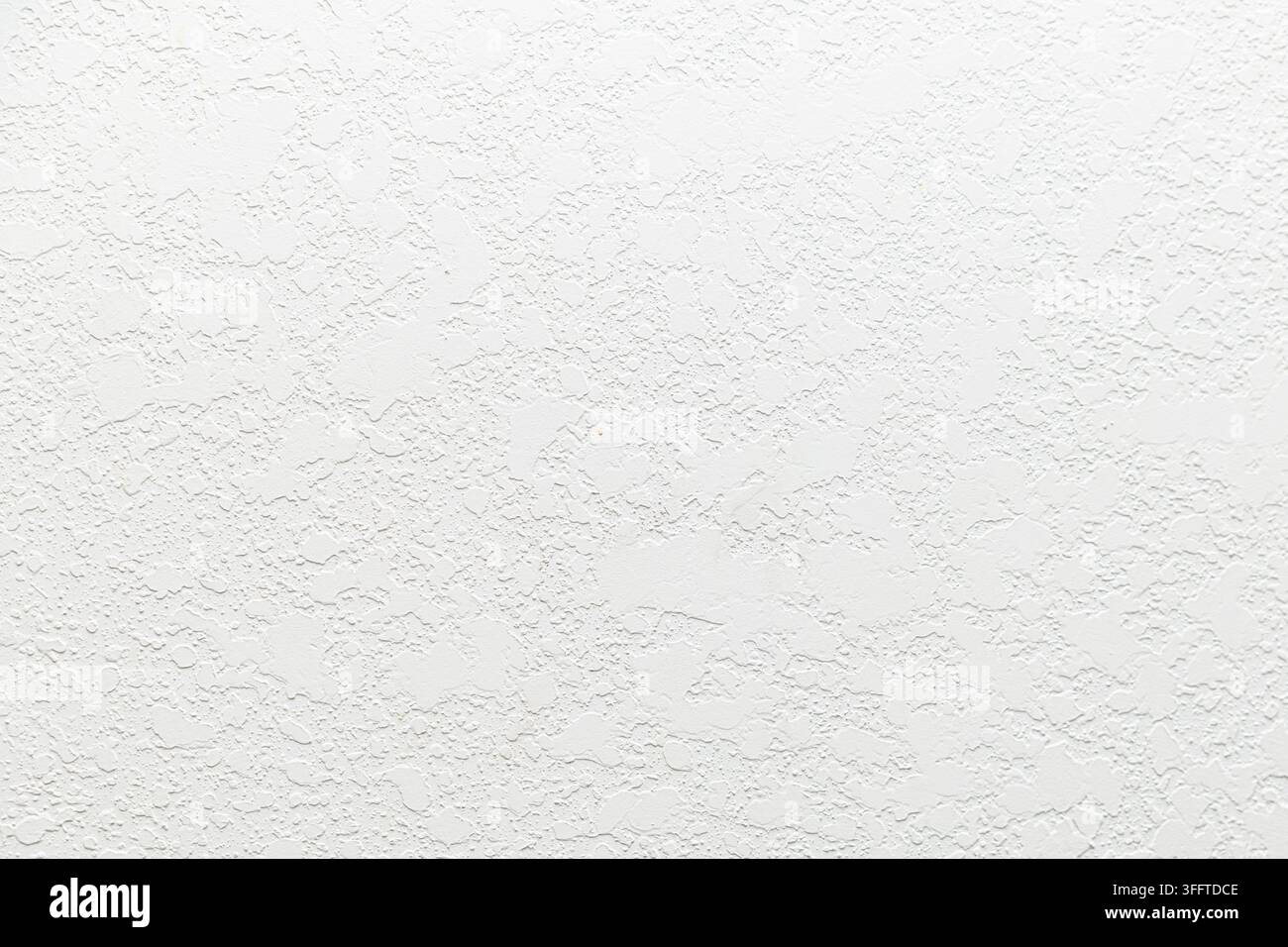 White textured wall surface with irregular raised plaster pattern, neutral backdrop, minimal background, abundant copy space. Stock Photo