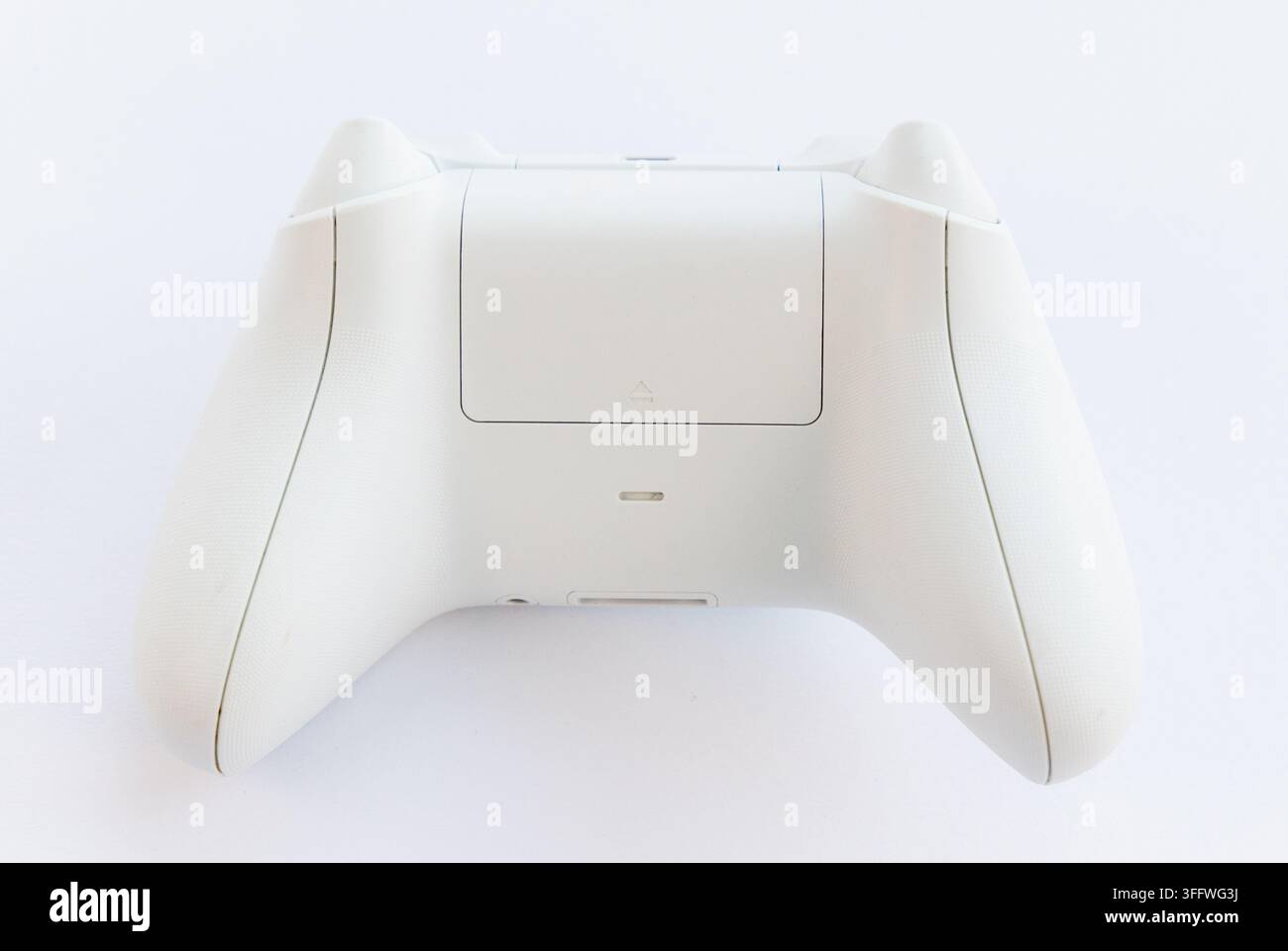 The rear side of a white gaming controller is shown Stock Photo