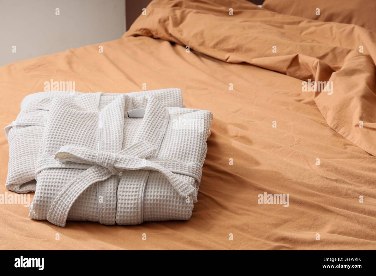 Folded waffle bathrobes on bed in room Stock Photo