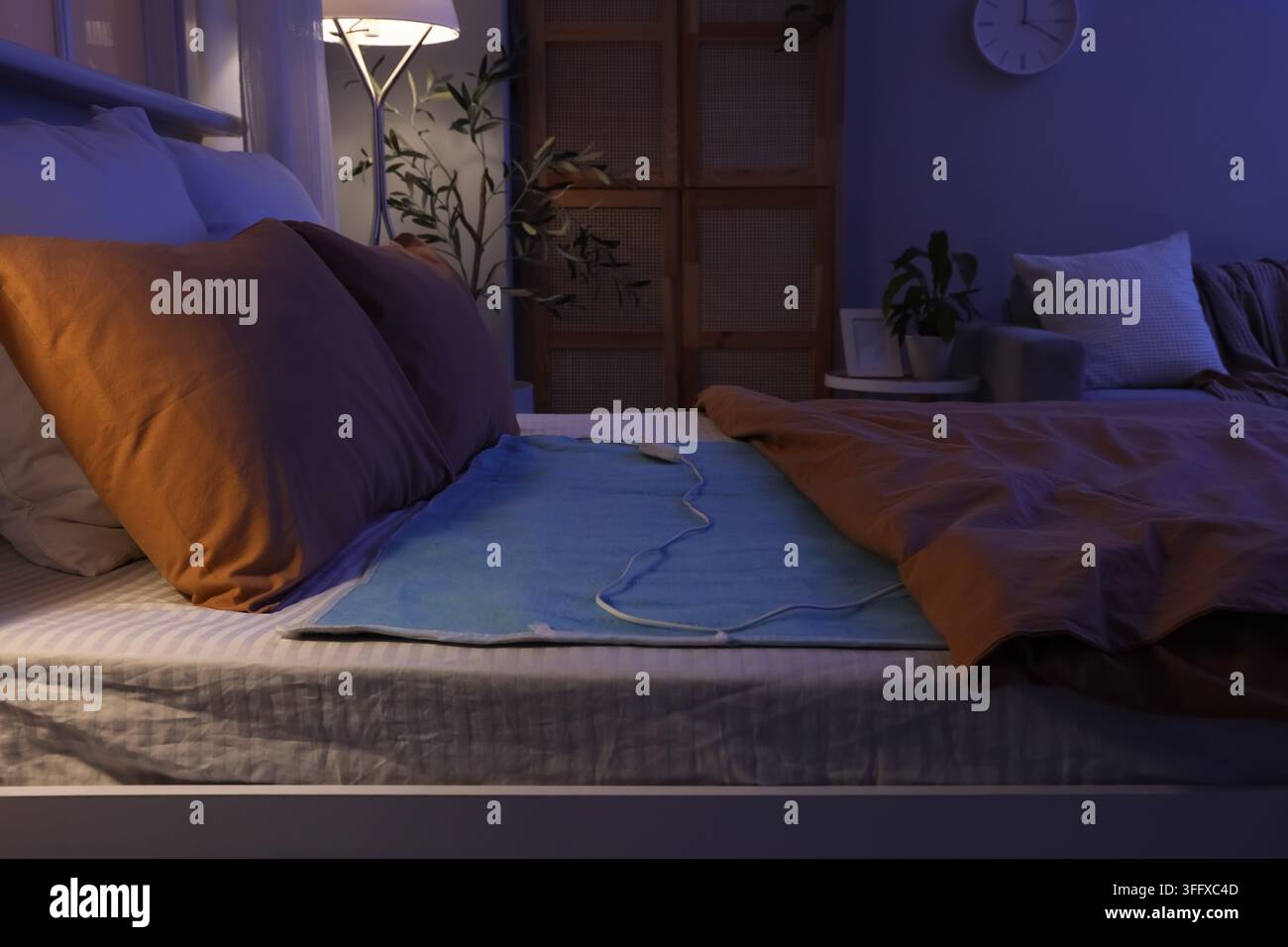 Electric heating pad on bed in dark room Stock Photo