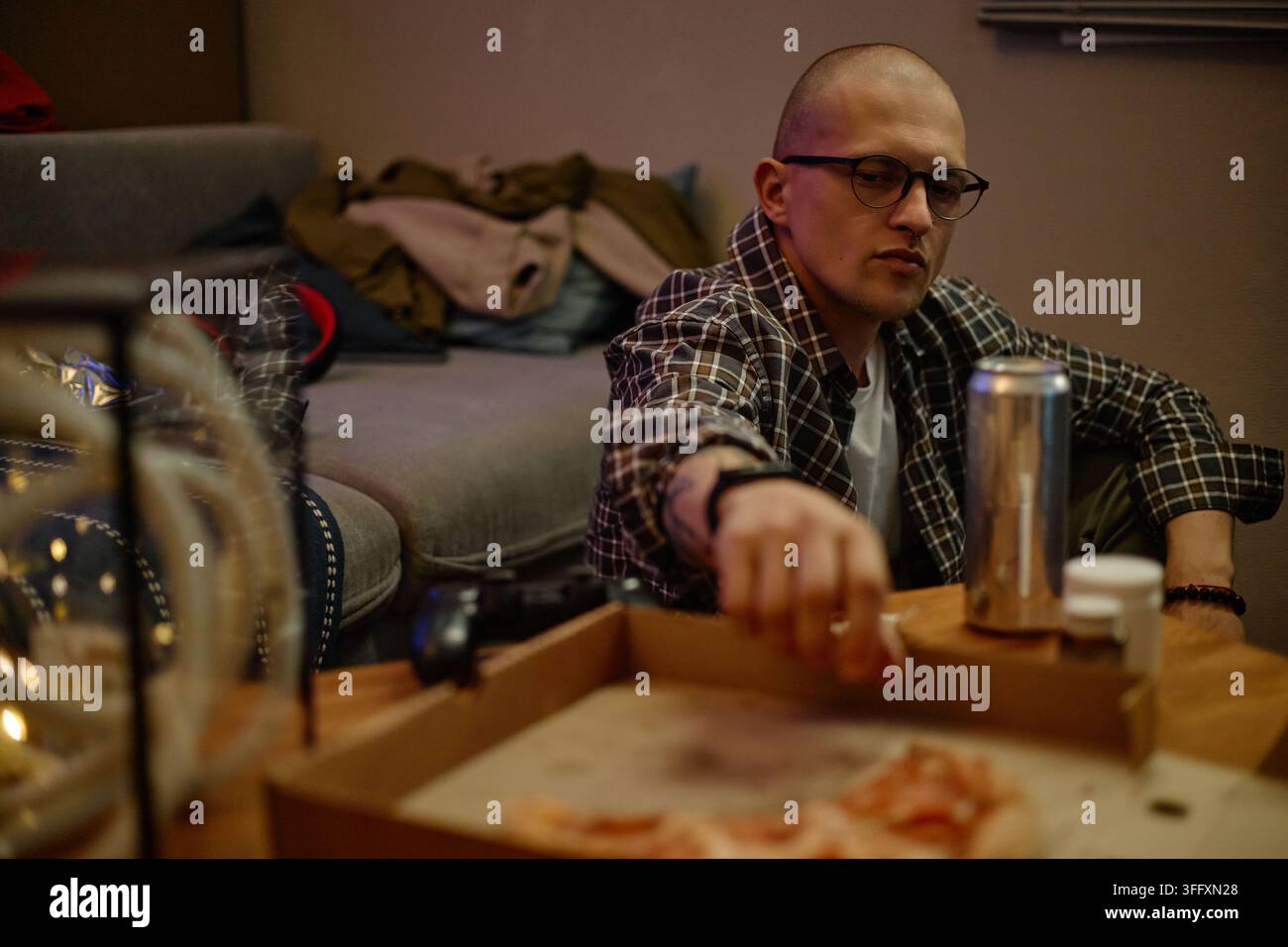 Man Reaching for Pizza While Playing Video Games at Home Stock Photo