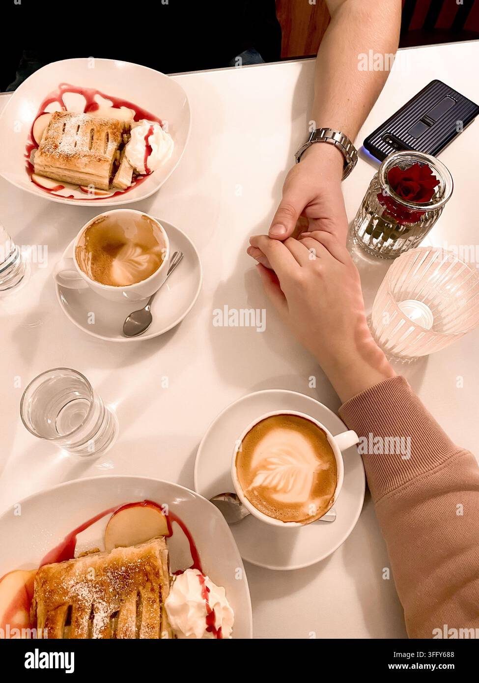 Two hands held together male and female on the table at breakfast with coffee and ice cream cake, date, feelings, top view Stock Photo