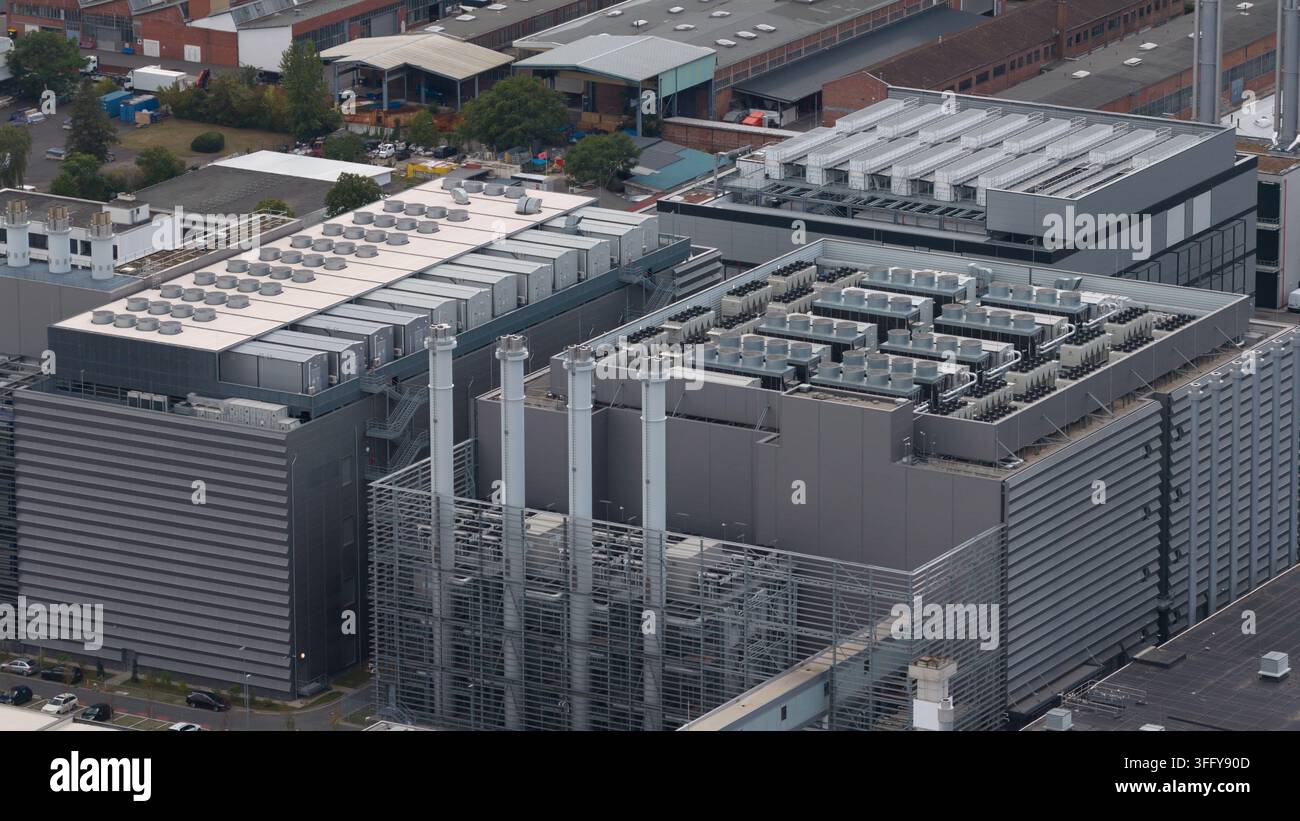 Aerial view of a large data center with multiple cooling units on the roof, tall ventilation chimneys, and metal facade structures in Frankfurt am Mai Stock Photo