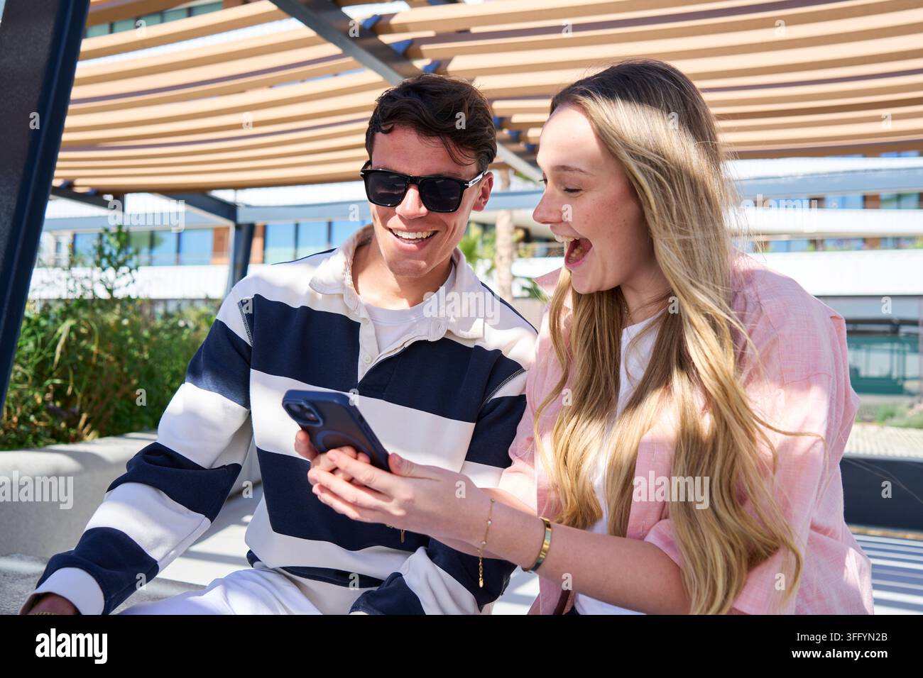 Young couple looking at a smartphone outdoors Stock Photo