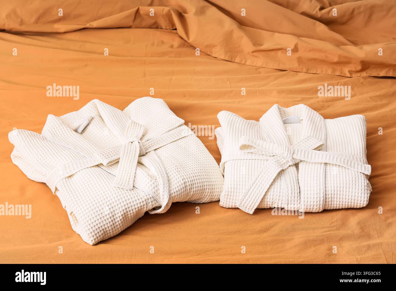 Folded waffle bathrobes on bed in room Stock Photo