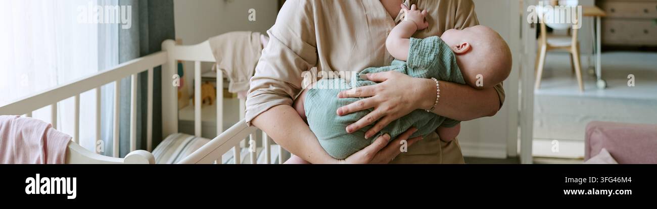 Mother Holding and Calming Sleeping Infant Baby at Home Stock Photo