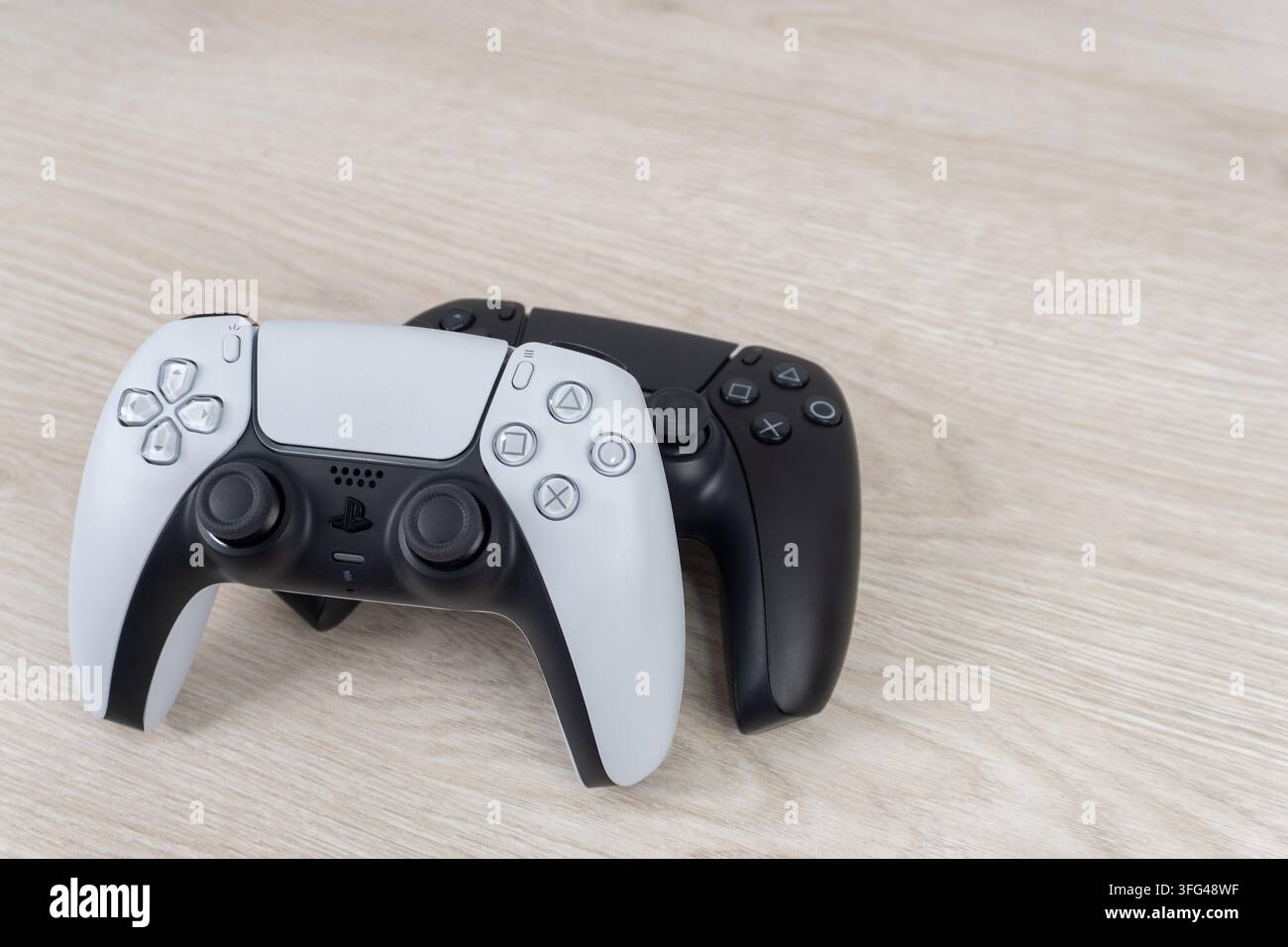 Bogota, Colombia - August 2026 White and black PS5 wireless controllers stacked on wooden surface Stock Photo