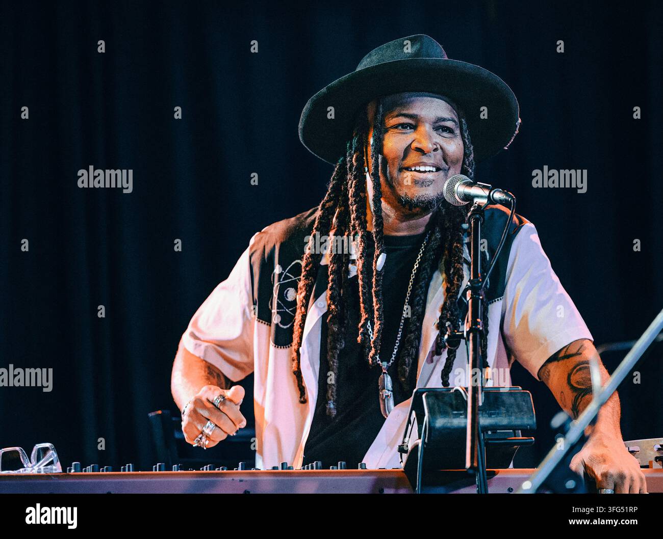 Smiling musician with dreadlocks playing keyboard on stage Stock Photo