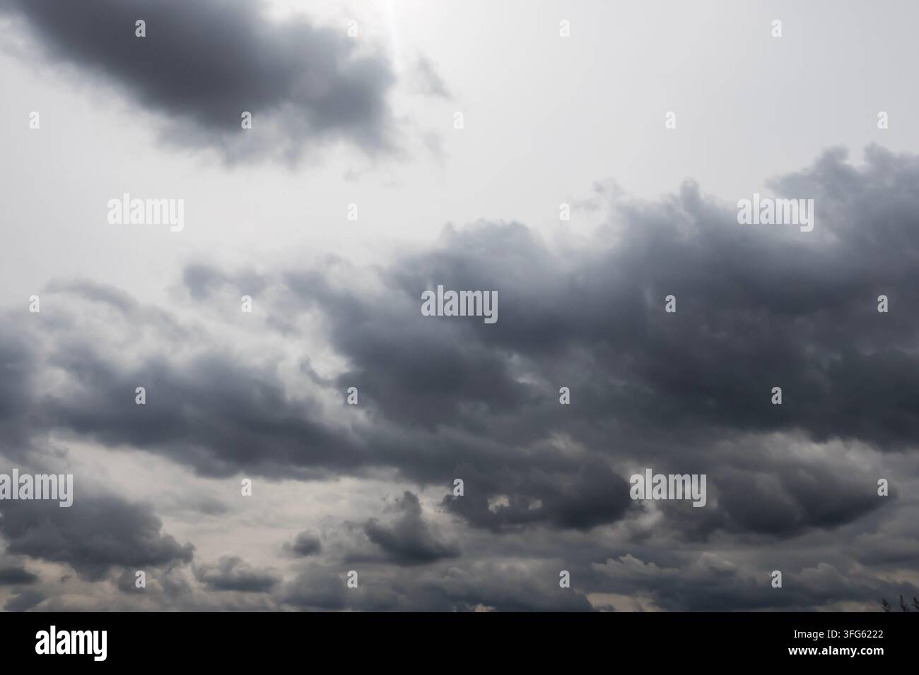 Dark storm clouds gather across a grey sky, creating a dramatic moody weather background with broad atmospheric copy space Stock Photo