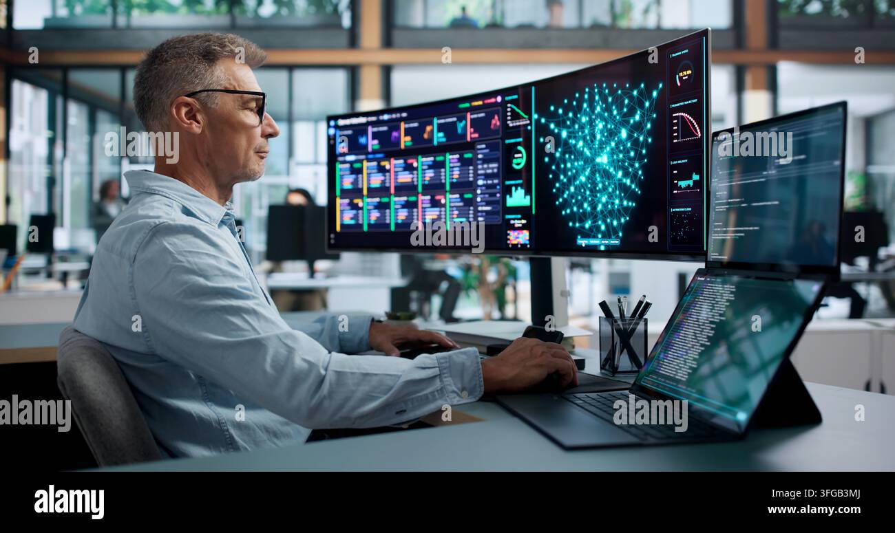 Data Scientist In Lab Coat Analyzing Neural Network Models On Dual Laptops. Stock Photo