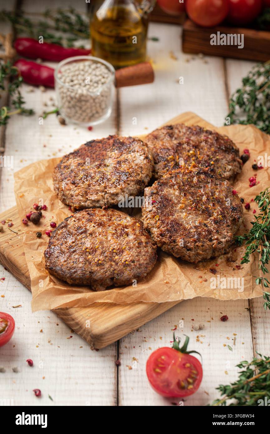 Fried beef cutlets on wooden board with herbs Stock Photo