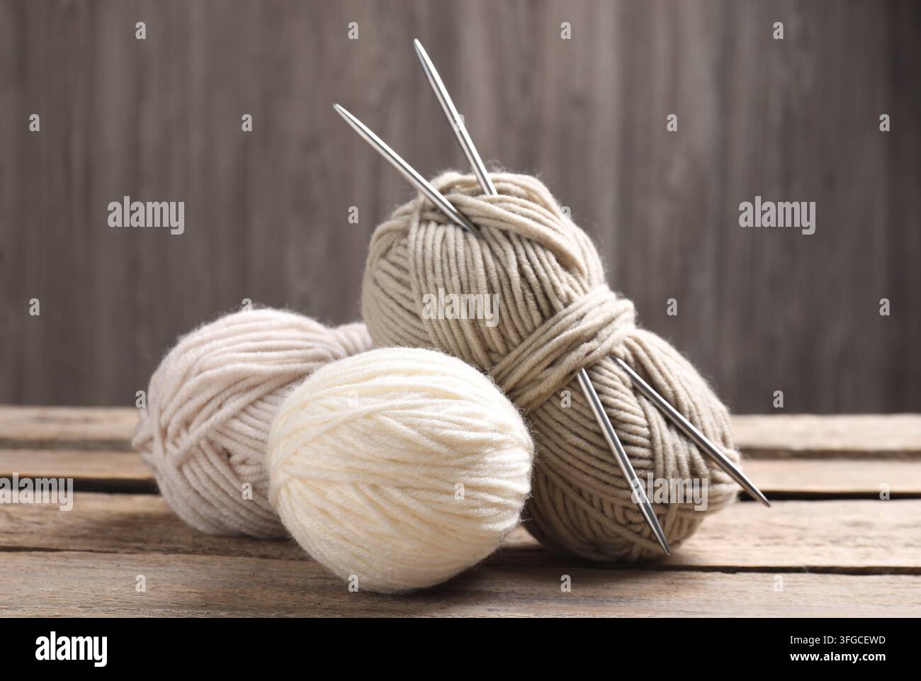 Knitting yarns and needles on wooden table, closeup Stock Photo