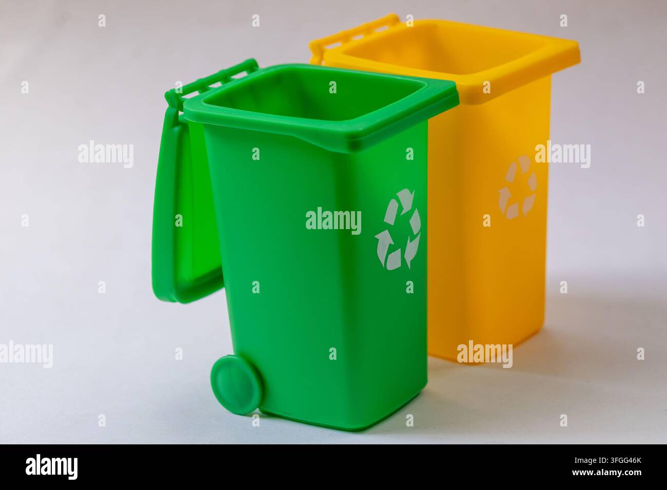 Two plastic recycling bins stand isolated on a white studio background. Stock Photo