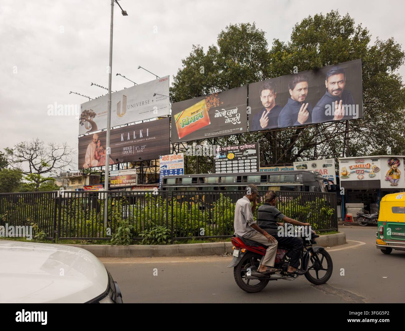 Vibrant urban street scene in Gujarat, India, featuring multiple billboards advertising various products and services. The bustling atmosphere include - Smartphone Captured Stock Image