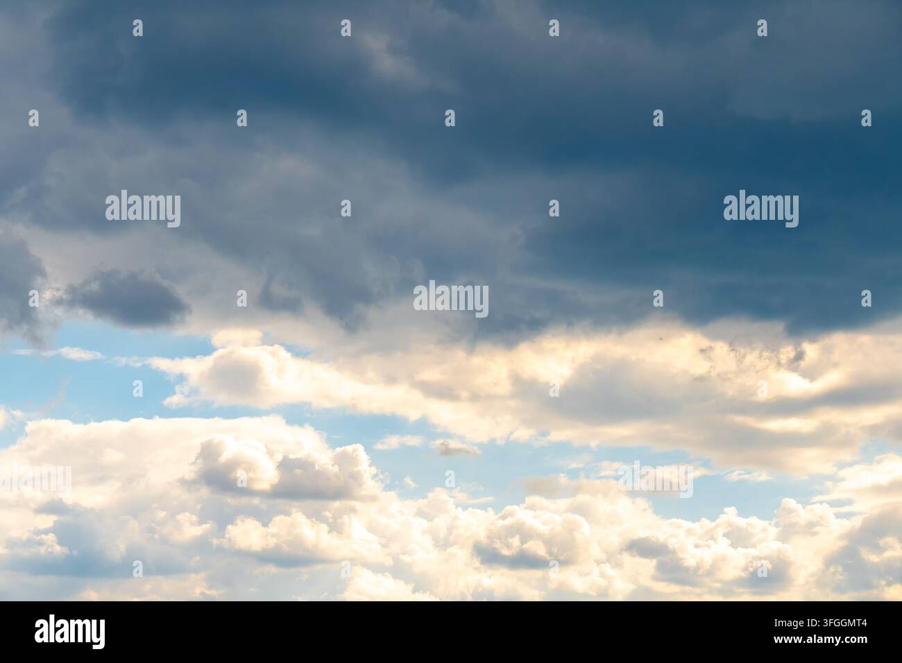 Dramatic clouds fill the sky with soft sunlight and a blue opening. Stock Photo