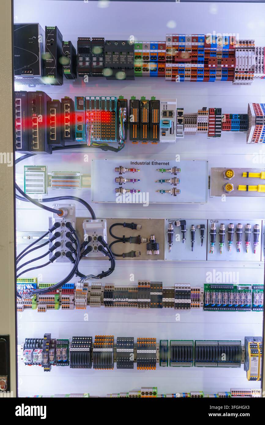 Inside an industrial electrical control panel featuring programmable logic controllers (PLC), Ethernet switches, terminal blocks, and complex wiring f Stock Photo