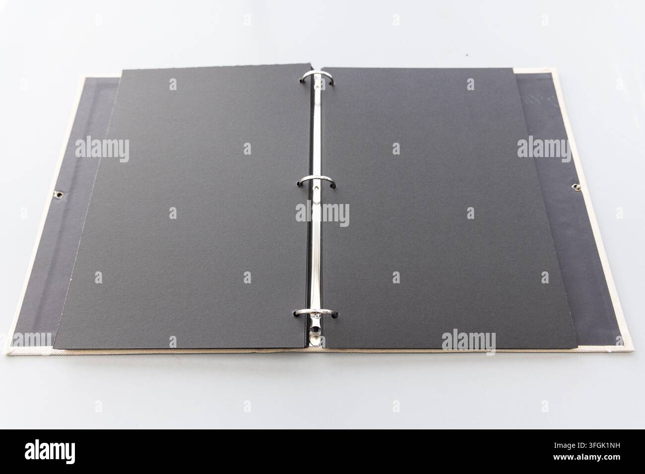 An open ring binder with black blank pages lies on white Stock Photo
