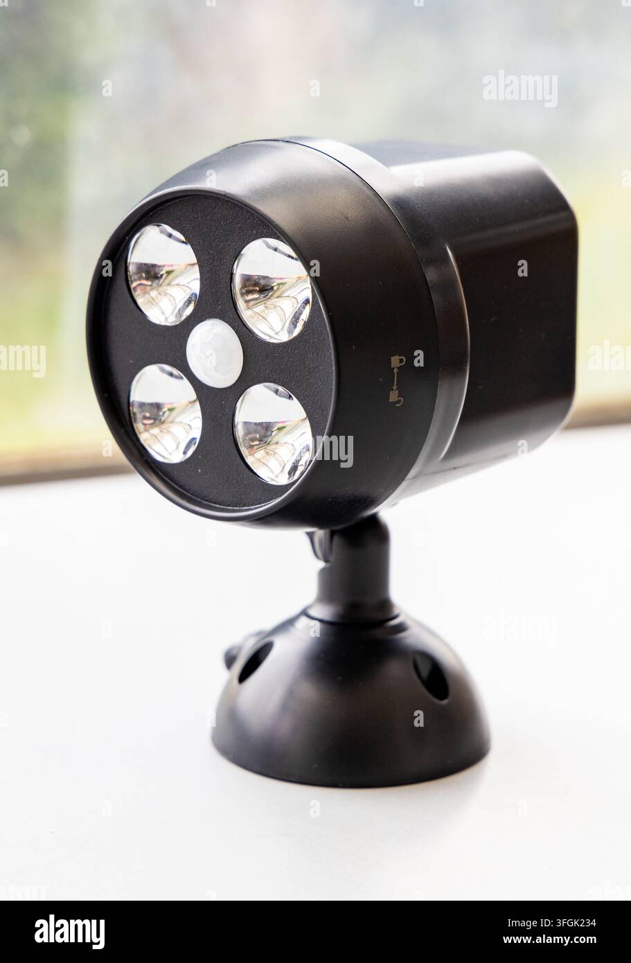 A black LED motion sensor spotlight stands on a white surface Stock Photo