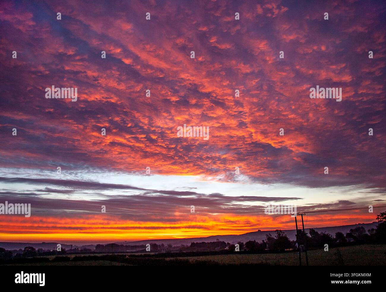 Sunset over Wingreen Hill in Dorset UK with fiery orange clouds glowing above the rolling countryside Stock Photo
