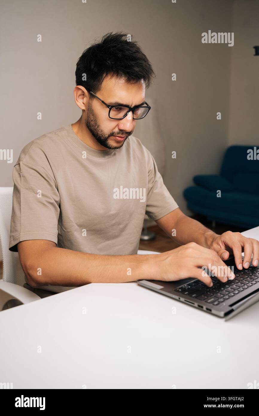 Vertical portrait of focused programmer male working typing code on laptop keyboard, showcasing process of software development and coding expertise. Stock Photo