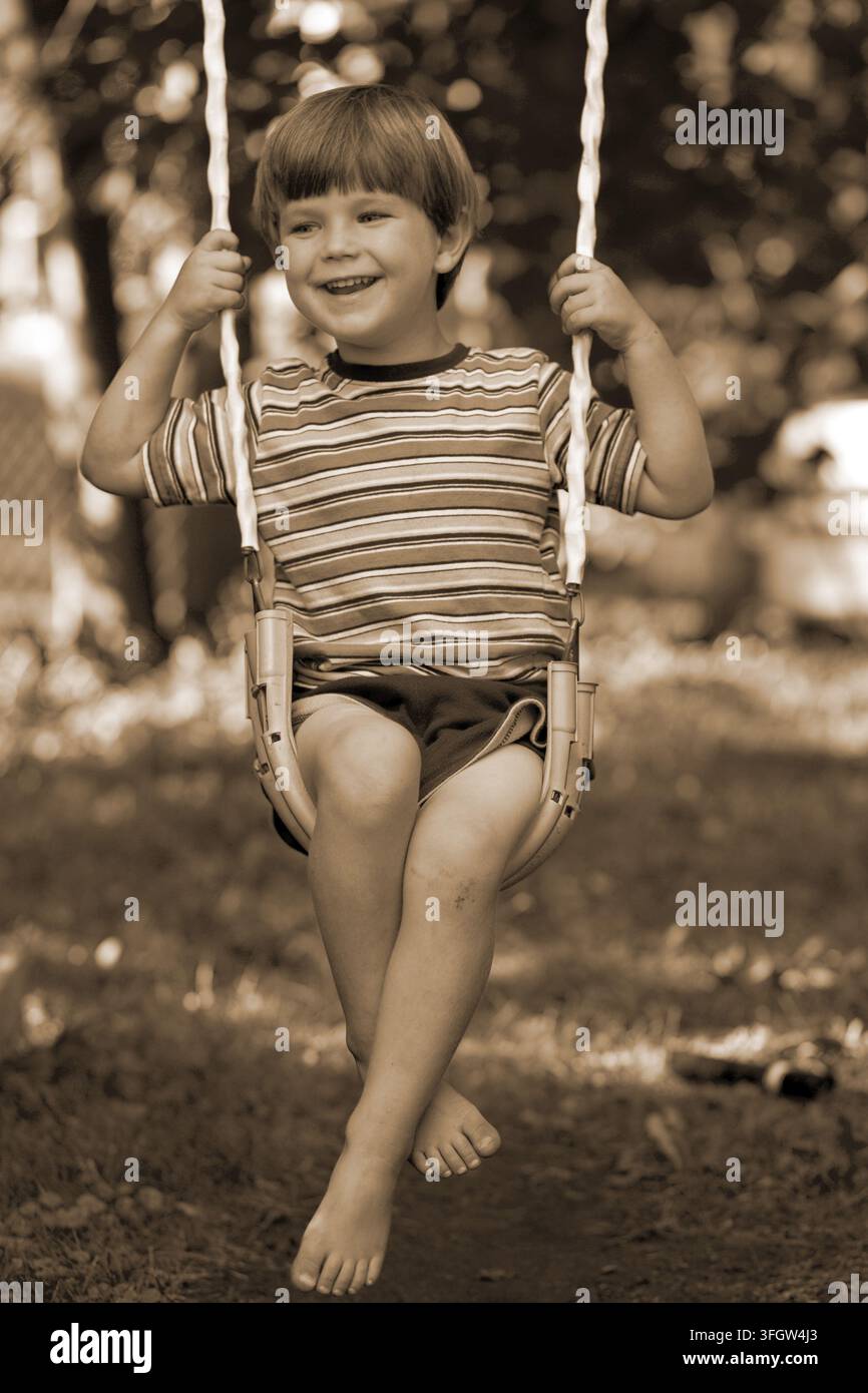 Child sitting on a swing smiling Stock Photo