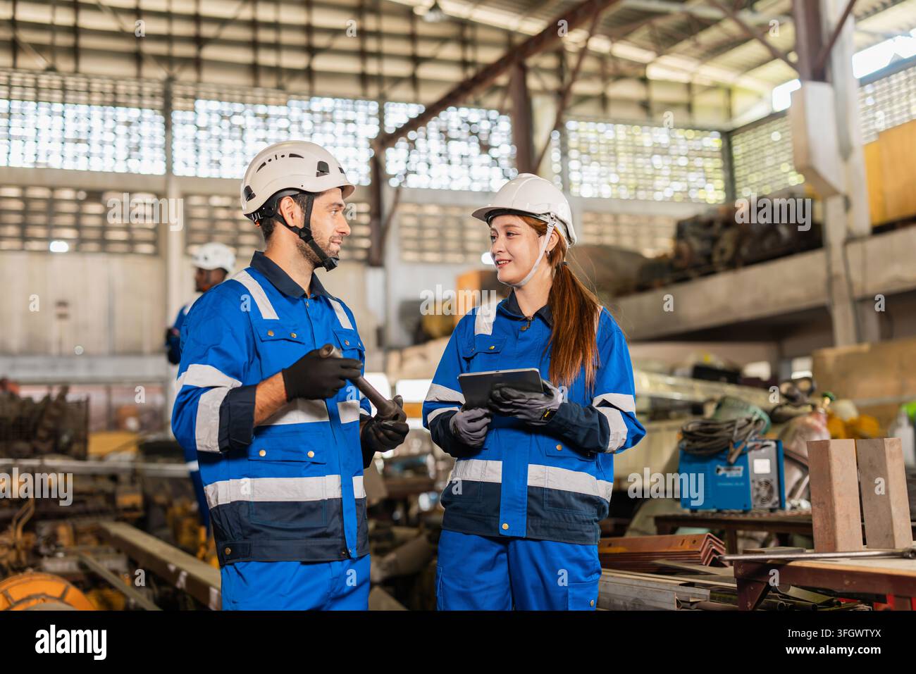 Factory Technicians Male and Female Talking Discussion Working together in Dirty Grunge Heavy Equipment Warehouse. Stock Photo