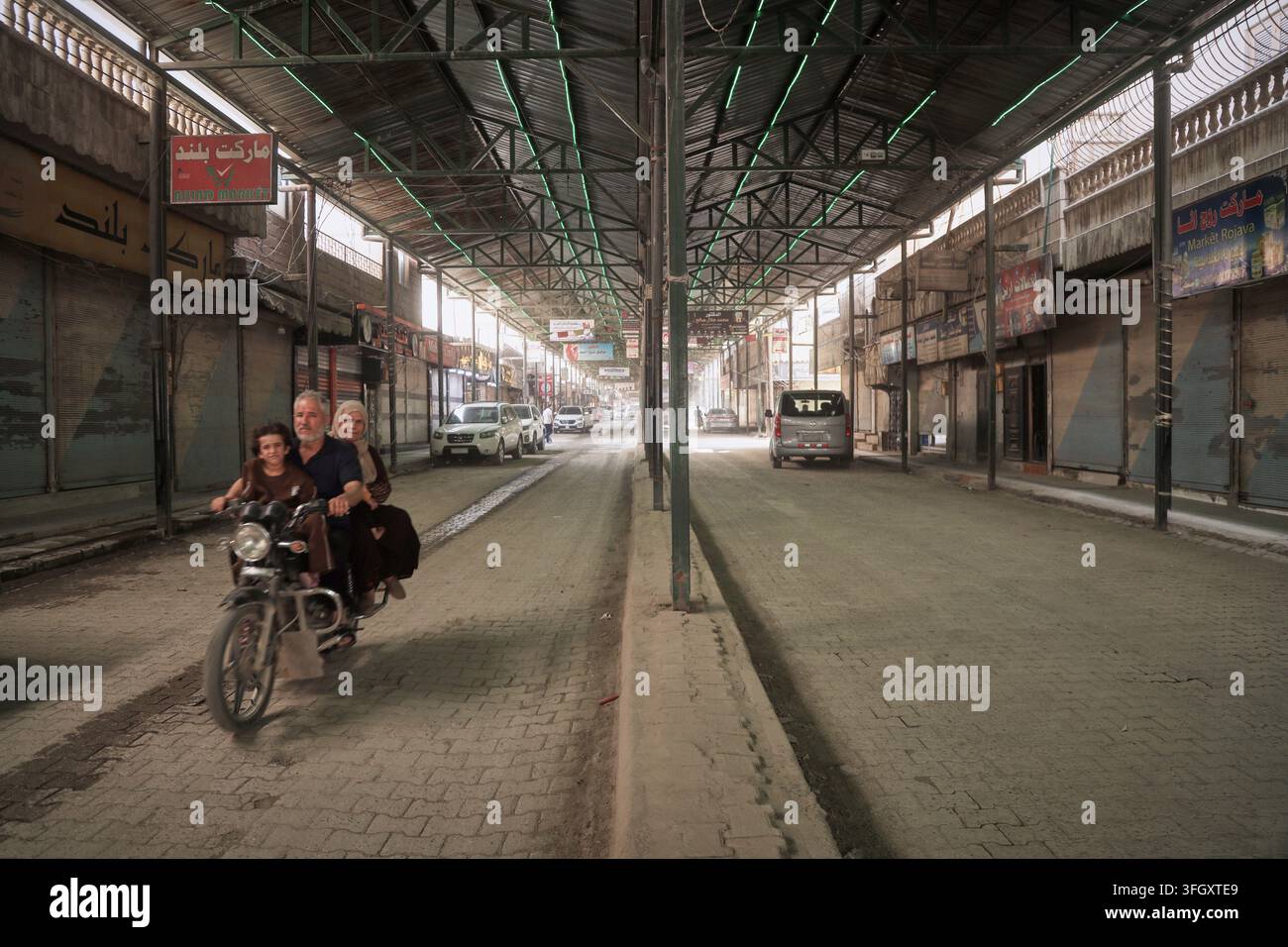 a-man-rides-a-motorcycle-through-a-largely-shuttered-market-in-kobani