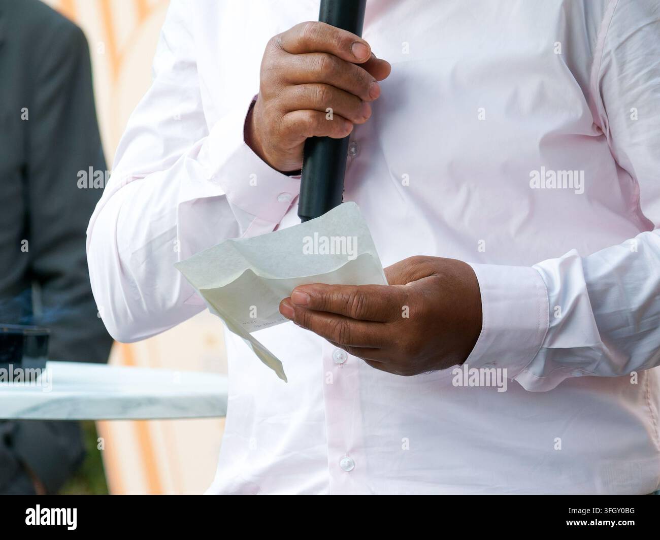 Person giving a speech with microphone and handwritten notes at a formal event Stock Photo