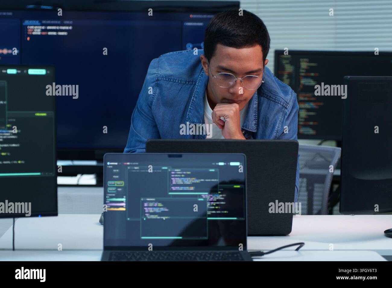 Focused programmer working on software development, digital technology, artificial intelligence, and cybersecurity code using a laptop. Stock Photo