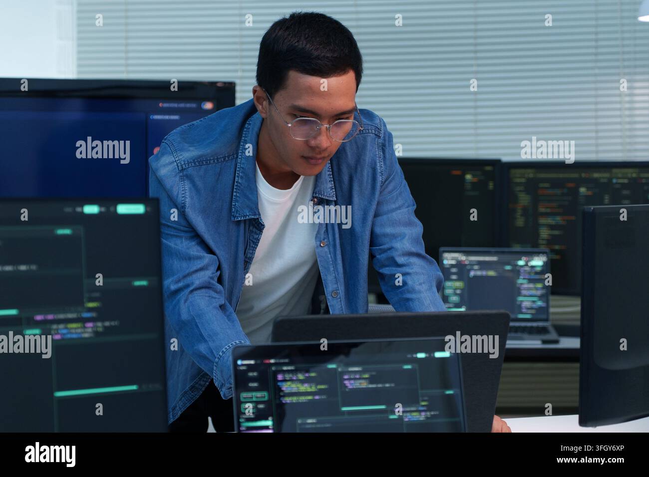 Focused programmer analyzing code and developing digital software solutions across multiple screens, representing modern technology, artificial intell Stock Photo