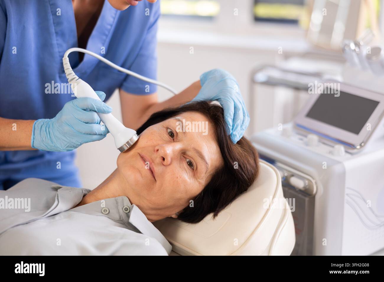 Aged female patient receiving facial procedure with high frequency ...