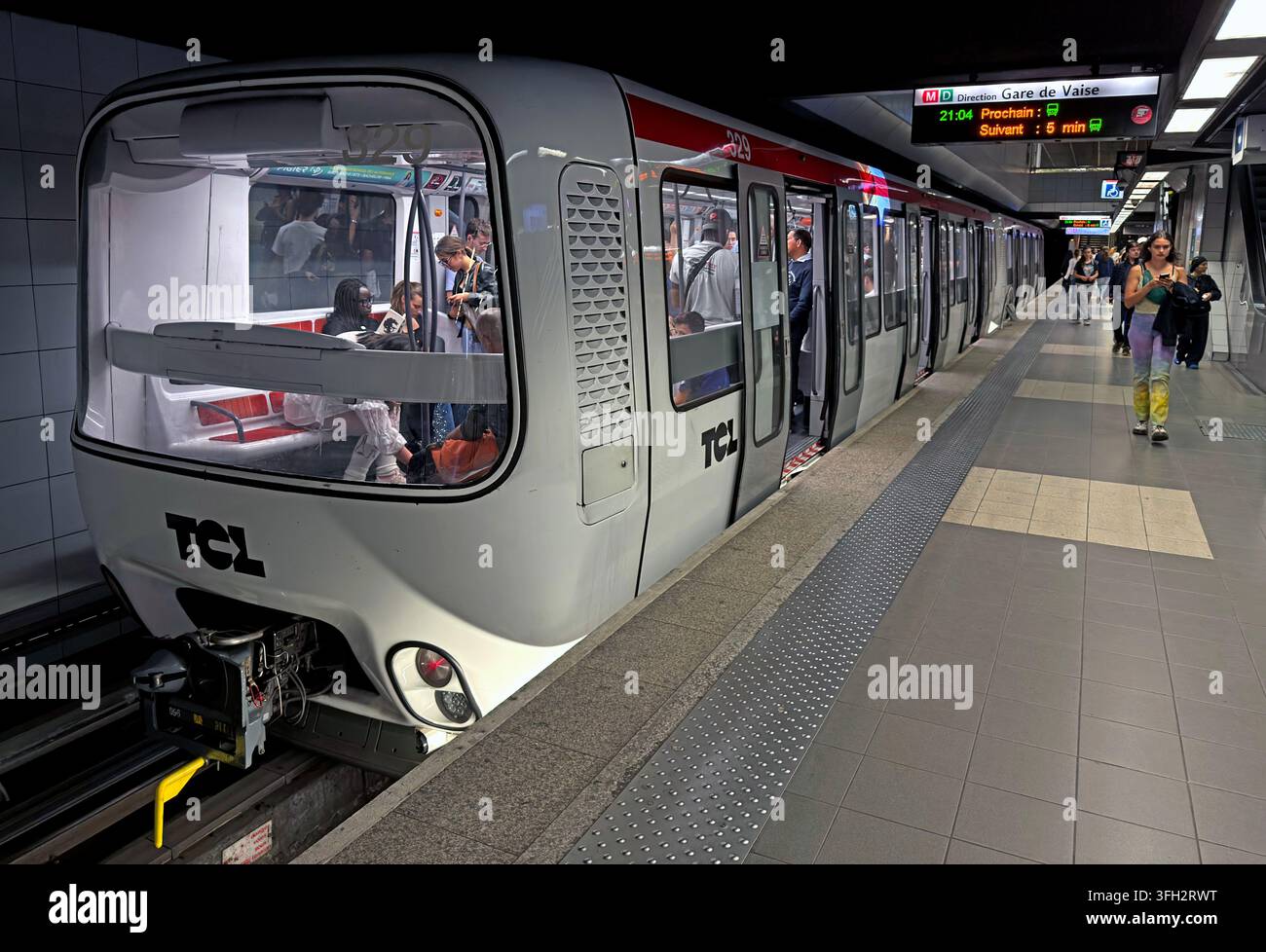 Passengers boarding a TCL Metro Line D train in Lyon, with platform information showing services through the city's rapid-transit network. Stock Photo