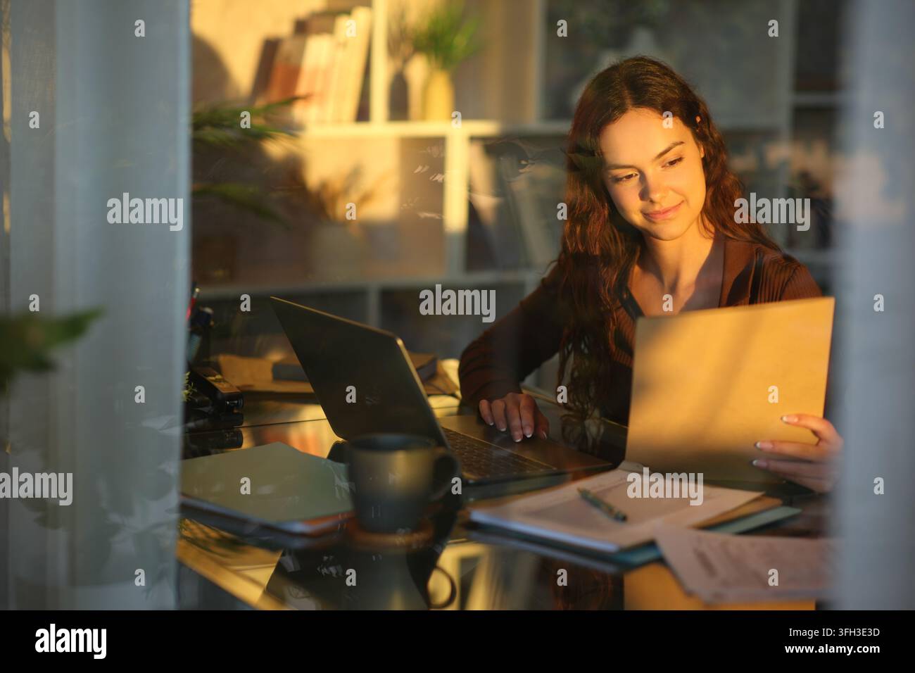 Telecommuter checking documents working at home viewed through a window Stock Photo