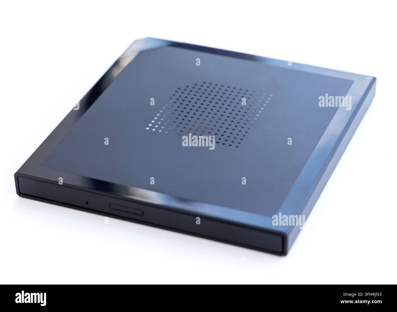 A black external optical drive with a perforated top rests on white Stock Photo