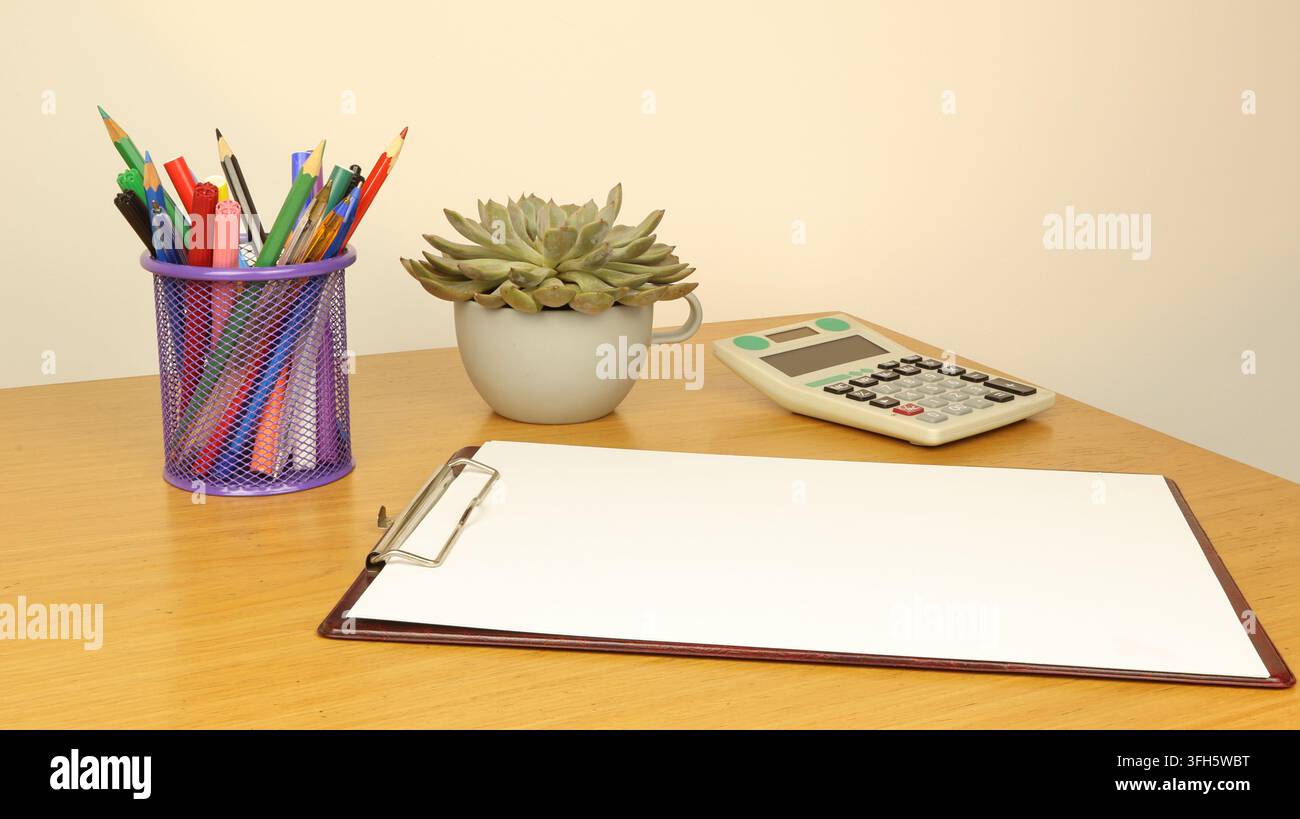 Side view of a workspace with a notebook and a blank page, a pen holder ...