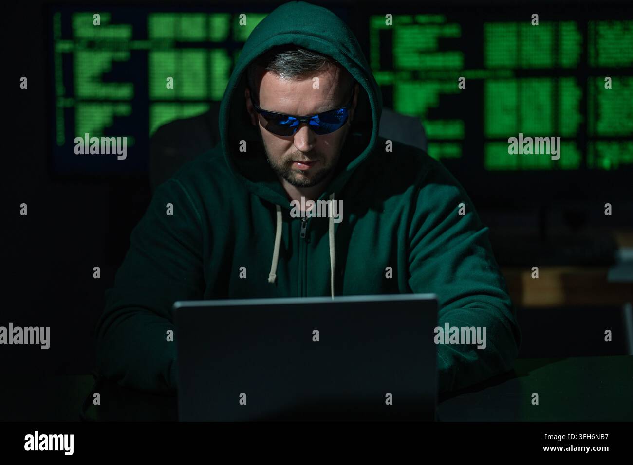 Hacker uses laptop for hacking activity. Hacker analyzes encryption and firewall system. Hacker monitors digital data flow. Hacker attempts identity Stock Photo