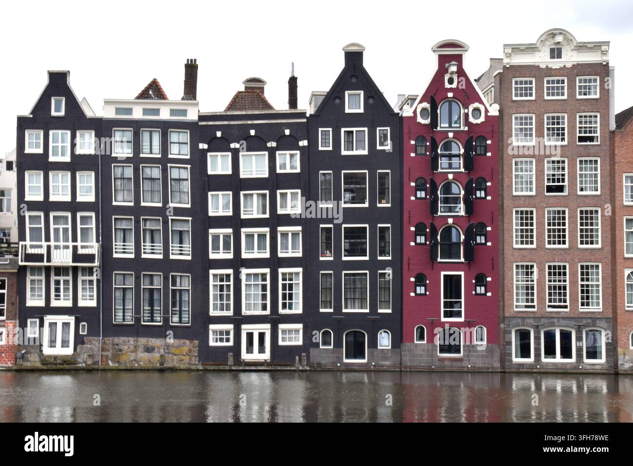 17th Century merchant houses on the Damrak waterfront in Amsterdam within the row of tilting and leaning houses known as the Dancing Houses of Damrak. Stock Photo