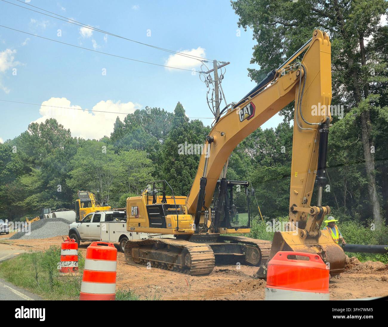 CAT excavator and construction worker at a roadside infrastructure work site - Smartphone Captured Stock Image