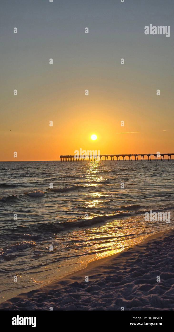 Golden sunset over the ocean with a fishing pier and sandy beach in Florida - Smartphone Captured Stock Image
