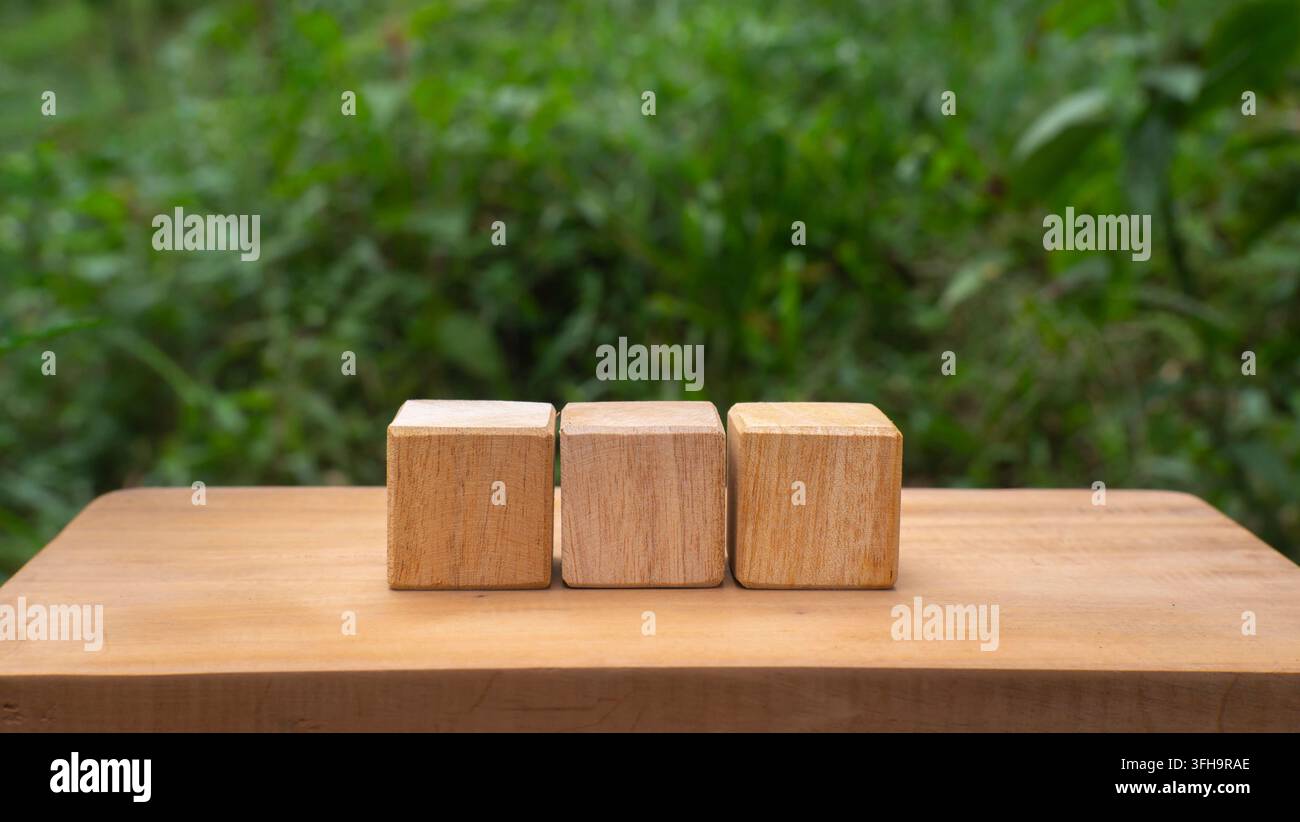 Three Wooden Cubes on Rustic Table with Green Nature Background Stock Photo