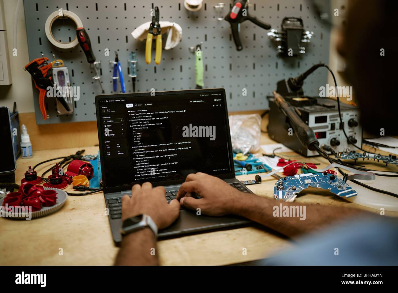 Man Programming Hardware and Coding on Laptop in Workshop Stock Photo