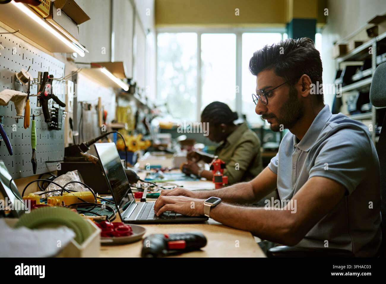 Indian Engineer Coding on Laptop in Hardware Workshop Stock Photo