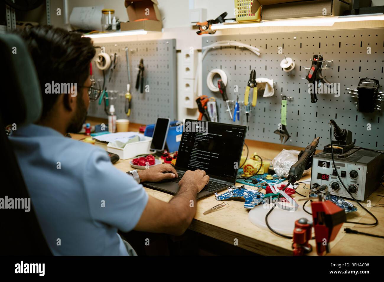 Indian Electronics Engineer Coding on Laptop in Hardware Workshop Stock Photo