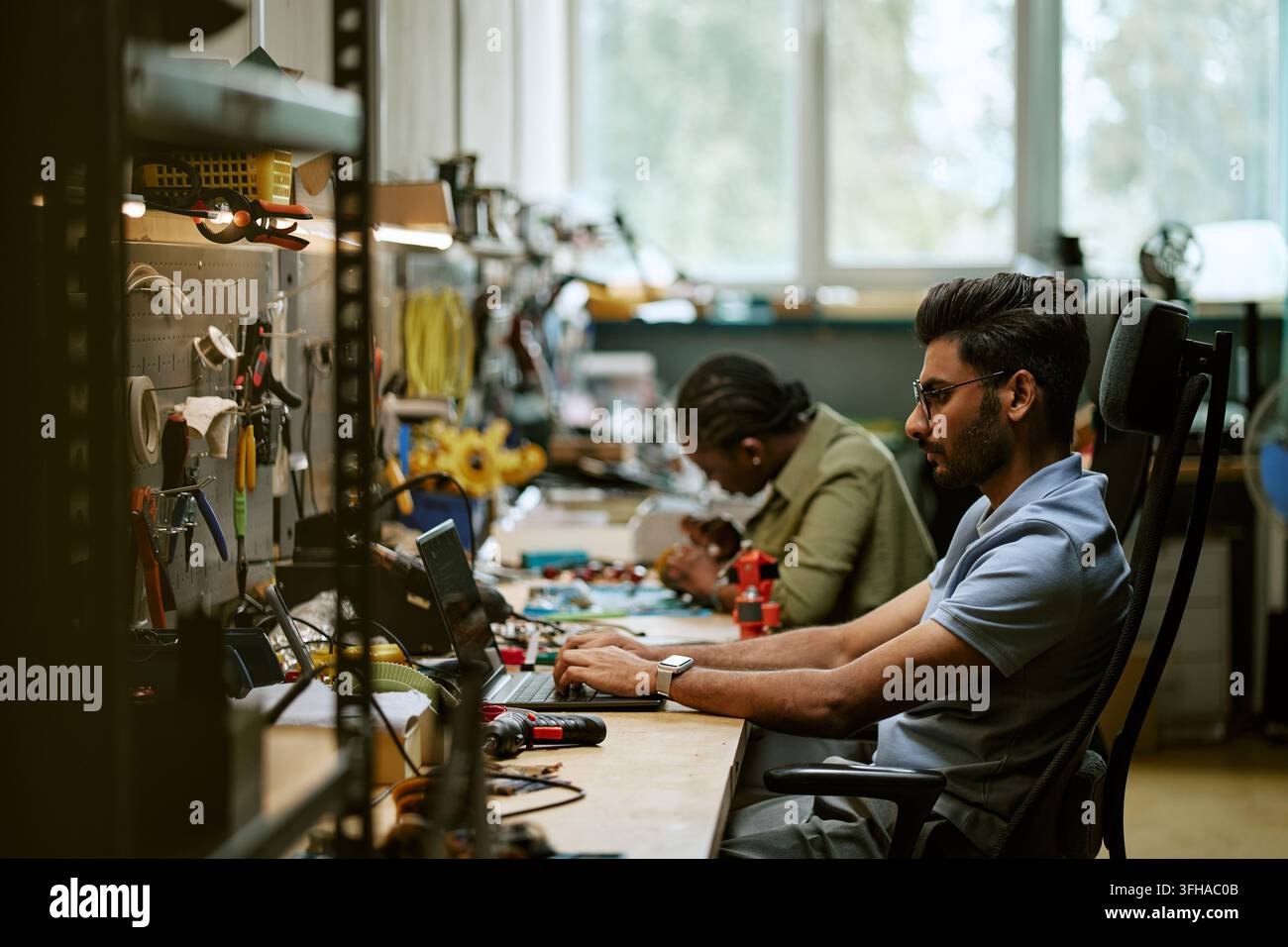 Indian Man Working on Laptop in Electronics Workshop Stock Photo
