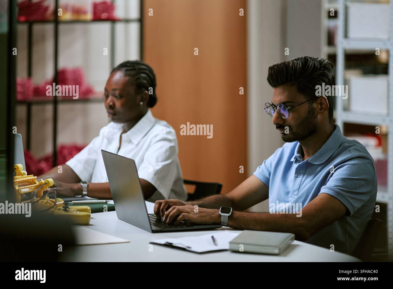 Diverse Colleagues Working on Laptops in Tech Workshop Office Stock Photo