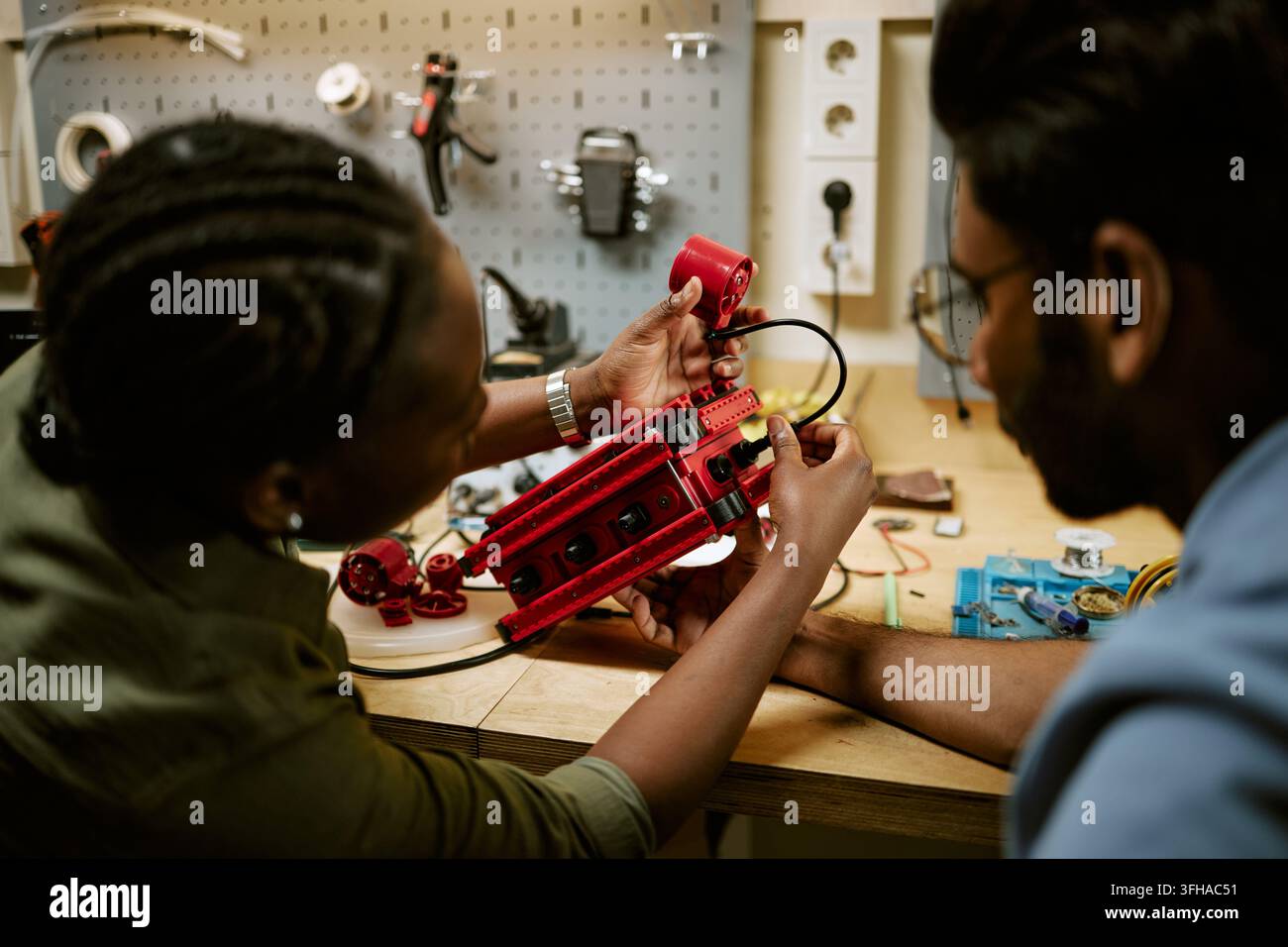 Diverse Engineers Assembling Robotic Prototype in Workshop Stock Photo